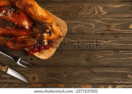 thanksgiving theme, grilled turkey on cutting board near cherry tomatoes and cutlery on wooden table