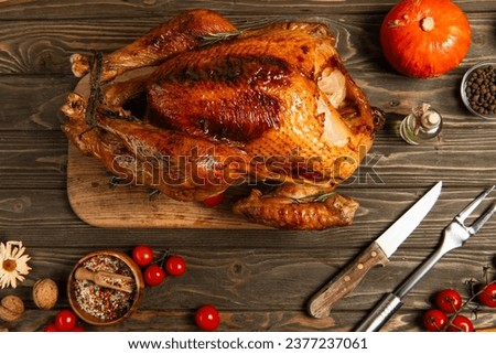 delicious thanksgiving, roasted turkey near cherry tomatoes, spices and cutlery on wooden tabletop