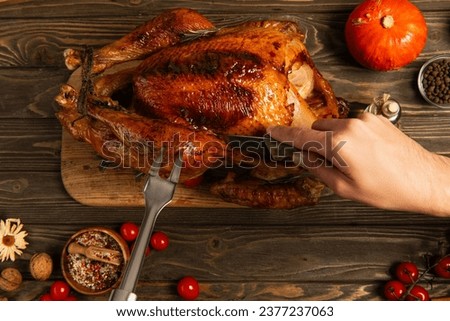 cropped view of man with knife and culinary fork cutting thanksgiving turkey on decorated table