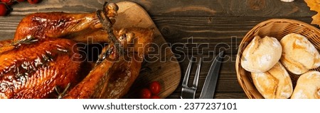 delicious thanksgiving turkey and freshly baked bread near cutlery on textured wooden table, banner
