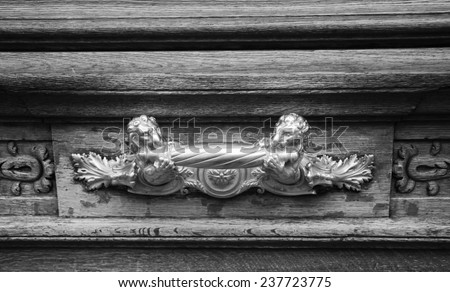 Royal style doorknocker on old wooden door (Paris, France) Two lions fighting for the same bone. ?ompetition in business concept. Aged photo. Black and white.