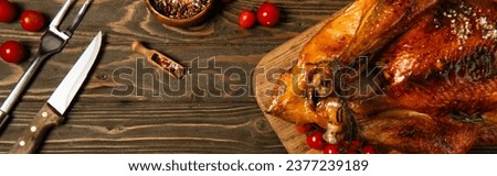 roasted thanksgiving turkey near spices, cutlery and red cherry tomatoes on wooden tabletop, banner