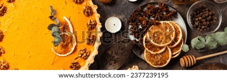 thanksgiving setting, pumpkin pie with walnuts and orange slices near spices on stone table, banner