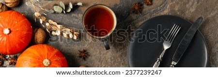 cup of aromatic tea near orange pumpkins and cutlery on black ceramic plate, thanksgiving, banner