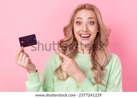 Photo of charming girlfriend wearing green sweatshirt enjoy her pointing cashless payment card astonished isolated on pink color background