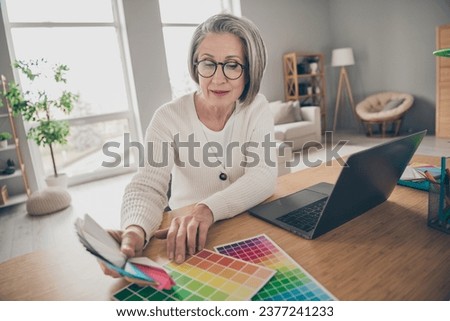 Photo of pretty shiny elderly lady wear white choosing renovation walls colors indoors apartment room
