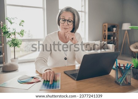 Photo of good mood thoughtful elderly lady designer wear white cardigan choosing architect colors indoors apartment room