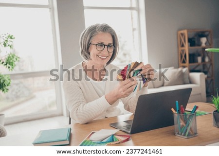 Photo of sweet shiny elderly lady wear white choosing new interior colors indoors apartment room