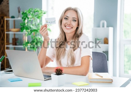Photo of charming lovely girl banker sitting modern room workspace hand showing bank card cashless payment online shopping