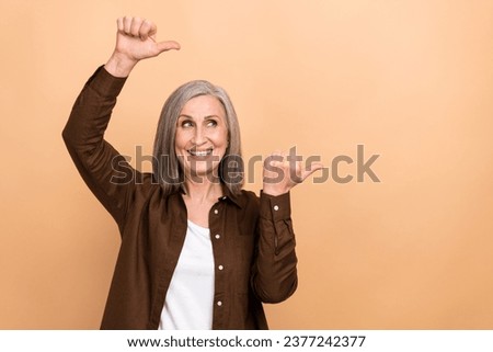 Portrait of pretty positive lady look indicate thumb fingers empty space ad isolated on beige color background