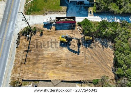 Aerial perspective of a yellow excavator preparing a vacant lot.  Royalty-Free Stock Photo #2377246041