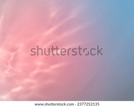 Light reflects off glass on a pastel pink and blue background for an abstract minimalist background.