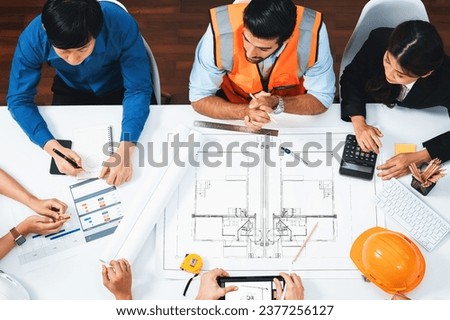 Top view banner of diverse group of civil engineer and client working together on architectural project, reviewing construction plan and building blueprint at meeting table. Prudent Royalty-Free Stock Photo #2377256127