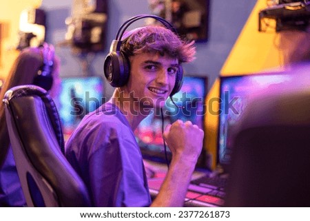 Portrait of young gamer boy ready to play online with his headset and neon blurred background