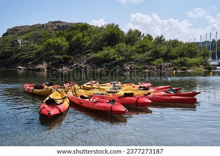 Stack of colorful kayaks moored on rippling water surface against shore with green lush plants on summer day in nature Royalty-Free Stock Photo #2377273187
