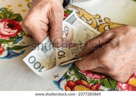Polish old woman pensioner clutches money in her hands, small amount, Concept, Difficult financial situation of elderly people in Poland, Rising fees and food prices Royalty-Free Stock Photo #2377285869