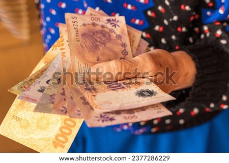 Argentinian money, a pensioner holds several pesos banknotes in her hand, Financial problems of seniors, low pensions in Argentina Royalty-Free Stock Photo #2377286229