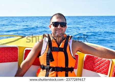 A man wearing sunglasses and sitting in a boat on a body of water. High quality photo