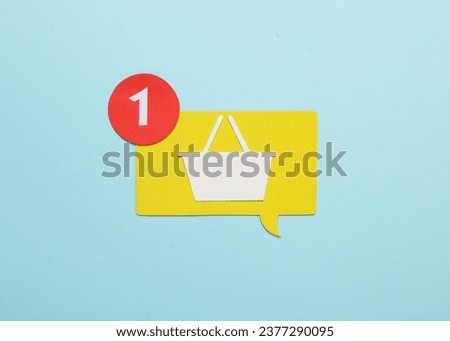 Paper cut notification speech bubble and shopping basket on on blue background