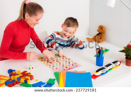 Preschooler boy playing in  board game with his mom