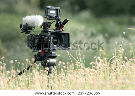 a movie camera or documentaries equipped with monitors for cinematographers. and a boom mic for recording good-quality sound. Placed in the middle of a flower field , Good environmental.