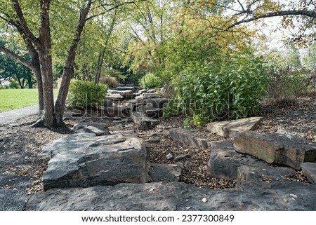 Large, gray boulders in a natural park wooded setting in autumn.