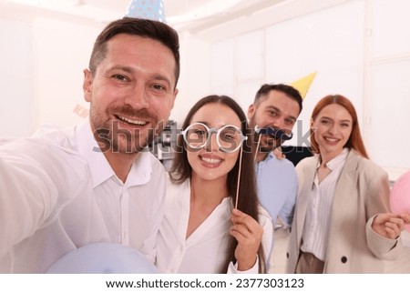 Coworkers taking selfie during office party indoors