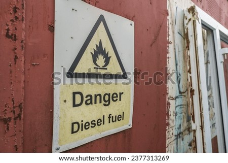 Danger diesel fuel sign mounted on a rusty red metal surface, information and safety concept illustration.