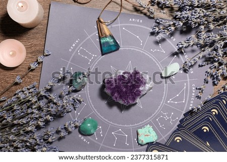Astrology prediction. Zodiac wheel, gemstones, tarot cards and burning candles on wooden table, flat lay Royalty-Free Stock Photo #2377315871