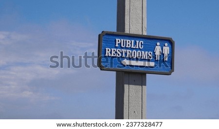 Wooden Public Restrooms sign against a blue sky at Stearns Wharf in Santa Barbara, California, USA