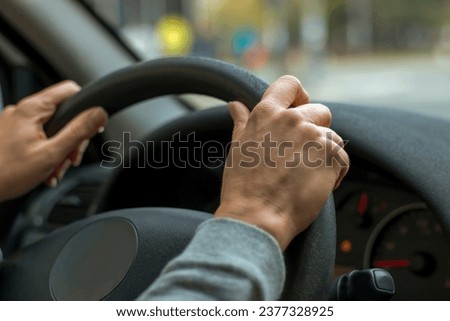 Female hand and steering wheel, closeup
