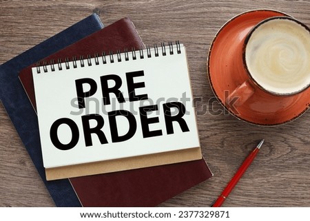 Pre Order Business concept. open notebook on a wooden table on two notebooks. orange mug with coffee. words