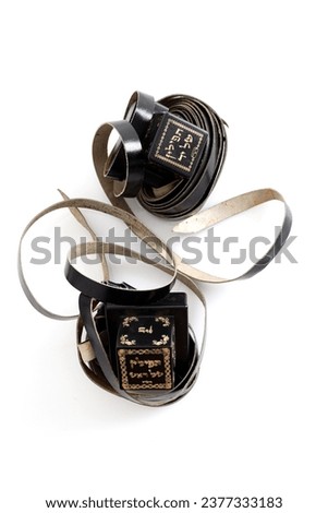 A photograph of ritual Jewish objects including prayer vestments with a hebrew inscription reading: On 1 object the symbols read: "Tefillin for the hand", on2 they read: "Tefillin for the head" Royalty-Free Stock Photo #2377333183