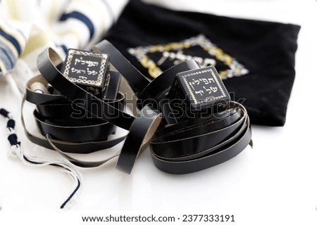 A photograph of ritual Jewish objects including prayer vestments with a hebrew inscription reading: On 1 object the symbols read: "Tefillin for the hand", on2 they read: "Tefillin for the head" Royalty-Free Stock Photo #2377333191