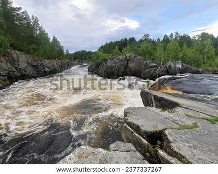 The famous powerful and wide Karelian waterfall Voitsky Padun in summer surrounded by rocks and greenery. Royalty-Free Stock Photo #2377337267