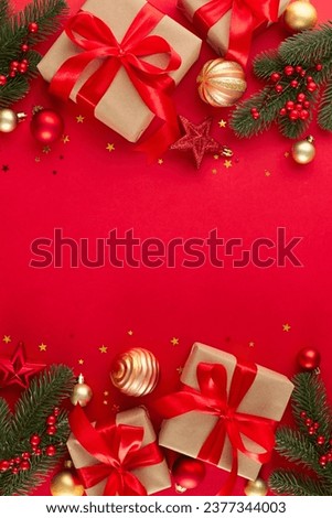 Start your Christmas shopping adventure today. Top view vertical composition of festive present boxes, tree decorations, fir twigs, shiny stars on red background with advert space