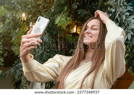 Beautiful cheerful young woman having a good time on a lovely day, taking a selfie, showing ok gesture