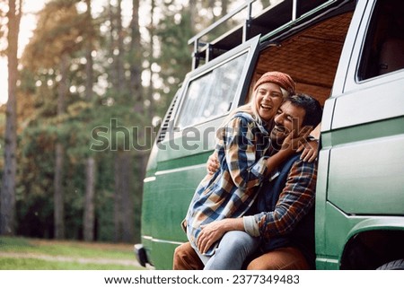 Happy couple laughing and having fun while camping in nature during autumn. Copy space. Royalty-Free Stock Photo #2377349483