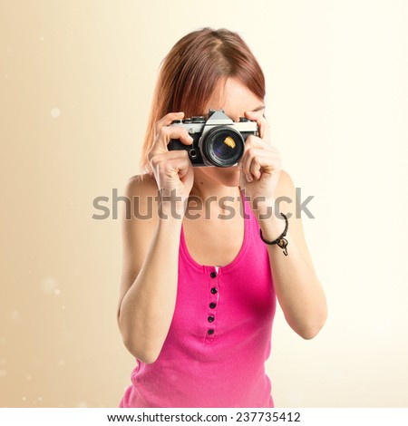 Girl taking a picture over ocher background 