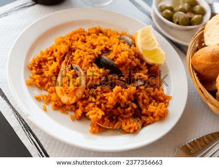 Appetizing racy seafood paella with mussels, prawns and slice of fresh lemon.Traditional Valencian cuisine Royalty-Free Stock Photo #2377356663