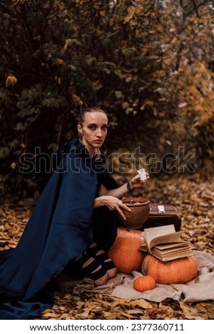 A young witch in the forest makes a spell, reads a book. Magic in the forest. Halloween. High quality photo