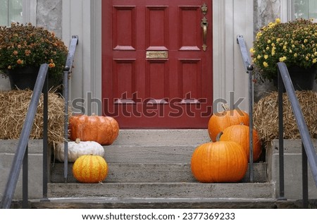 Front door with pumpkins and hay bale for fall or Thanksgiving decorations Royalty-Free Stock Photo #2377369233