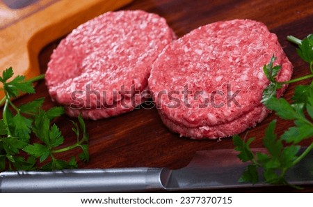 Image of raw burger cutlet and greens before cooking, nobody