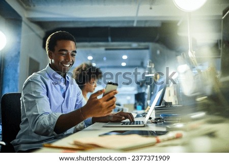 Young businessman typing on the laptop and using a smartphone in the office Royalty-Free Stock Photo #2377371909