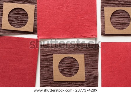 paper background consisting of texture brown and red cards arranged in a checkered form and paper tiles with circle cutouts