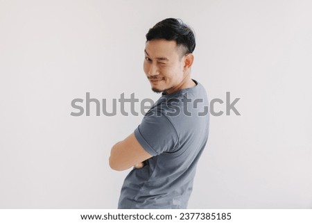 Happy asian man wears blue t-shirt and jeans winking at camera and smile. Royalty-Free Stock Photo #2377385185
