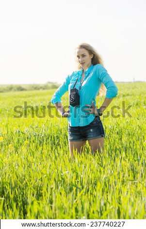young blond woman with vintage medium format photo camera in a green wheat field