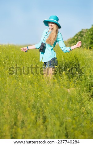 young blond woman with vintage medium format photo camera in a green wheat field feeling inspiration