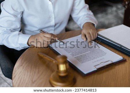 Hands of lawyer woman pointing on paper to reading legal agreement and signing on business contract.