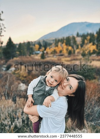 Photo shoot of a young mother of European appearance and little daughter against the background of autumn forest and mountains
